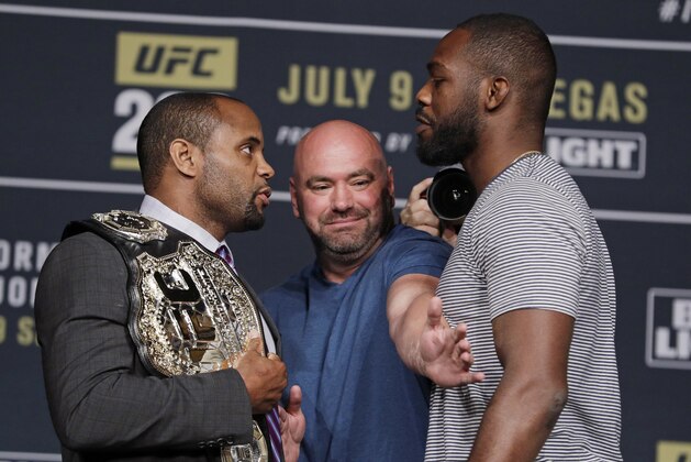 FILE - In this July 6, 2016, file photo, Dana White, center, stands between Daniel Cormier, left, and Jon Jones during a UFC 200 mixed martial arts news conference, in Las Vegas. Daniel Cormier still fights in the shadow of disgraced ex-champion Jon Jones. Cormier defends the UFC light heavyweight championship Saturday, Jan. 20, 2018, in UFC 220 against Volkan Oezdemir. But Cormier must still answer to the fact he has never defeated Jones.  (AP Photo/John Locher, File)