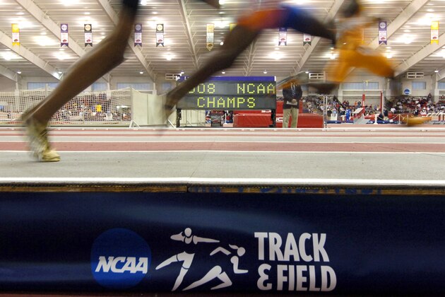 Tennessee's Evander Wells, far right, Florida's Willie Perry, center, and Long Beach State's Brent Gray, far left, race past a sign during a preliminary heat of the 200 meters at the NCAA indoor track and field championships in Fayetteville, Ark., Friday, March 14, 2008. (AP Photo/April L. Brown)