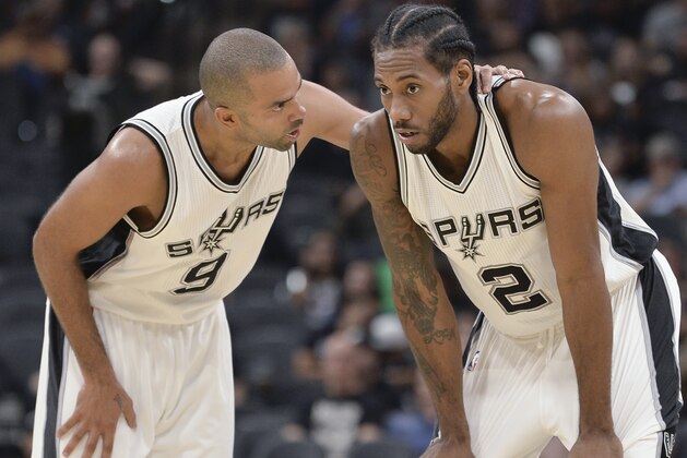 San Antonio Spurs guard Tony Parker (9), of France, talks with forward Kawhi Leonard during the second half of the team's preseason NBA basketball game against the Houston Rockets, Friday, Oct. 21, 2016, in San Antonio. (AP Photo/Darren Abate)