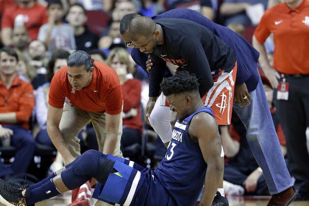Minnesota Timberwolves guard Jimmy Butler (23) reacts to a knee injury on the court as Houston Rockets guard Chris Paul (3) and team trainers hover over him during the second half of an NBA basketball game Friday, Feb. 23, 2018, in Houston. (AP Photo/Michael Wyke)