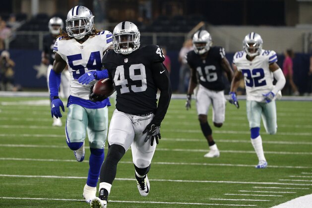 Oakland Raiders fullback Jamize Olawale (49) reaches for his left leg as he heads to the sideline after returning a punt as Dallas Cowboys linebacker Jaylon Smith (54) gives chase in the first half of a preseason NFL football game, Saturday, Aug. 26, 2017, in Arlington, Texas. The play was called back due to a Raiders penalty. (AP Photo/Michael Ainsworth)
