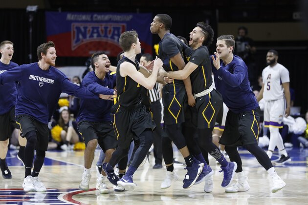 Graceland's Justin Harley, center, celebrates his game-winning overtime basket with Dalton Payton, left, Waseem Limbada, right, and other teammates in the NAIA men's championship college basketball game Tuesday, March 20, 2018, in Kansas City, Mo. Graceland defeated LSU Alexandria 83-80. (AP Photo/Colin E. Braley)