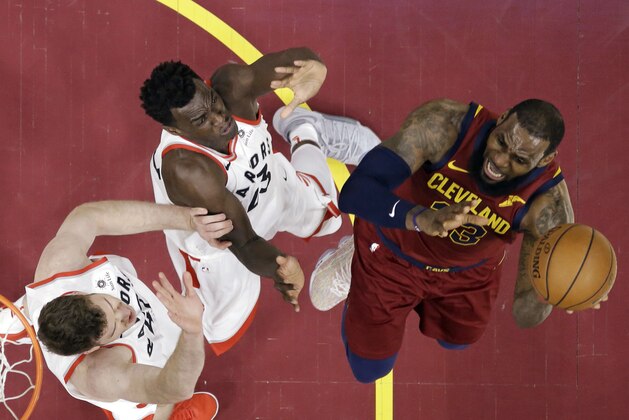 Toronto Raptors' Jakob Poeltl, left, and Pascal Siakam defend against Cleveland Cavaliers' LeBron James during the first half of an NBA basketball game Wednesday, March 21, 2018, in Cleveland. (AP Photo/Tony Dejak)