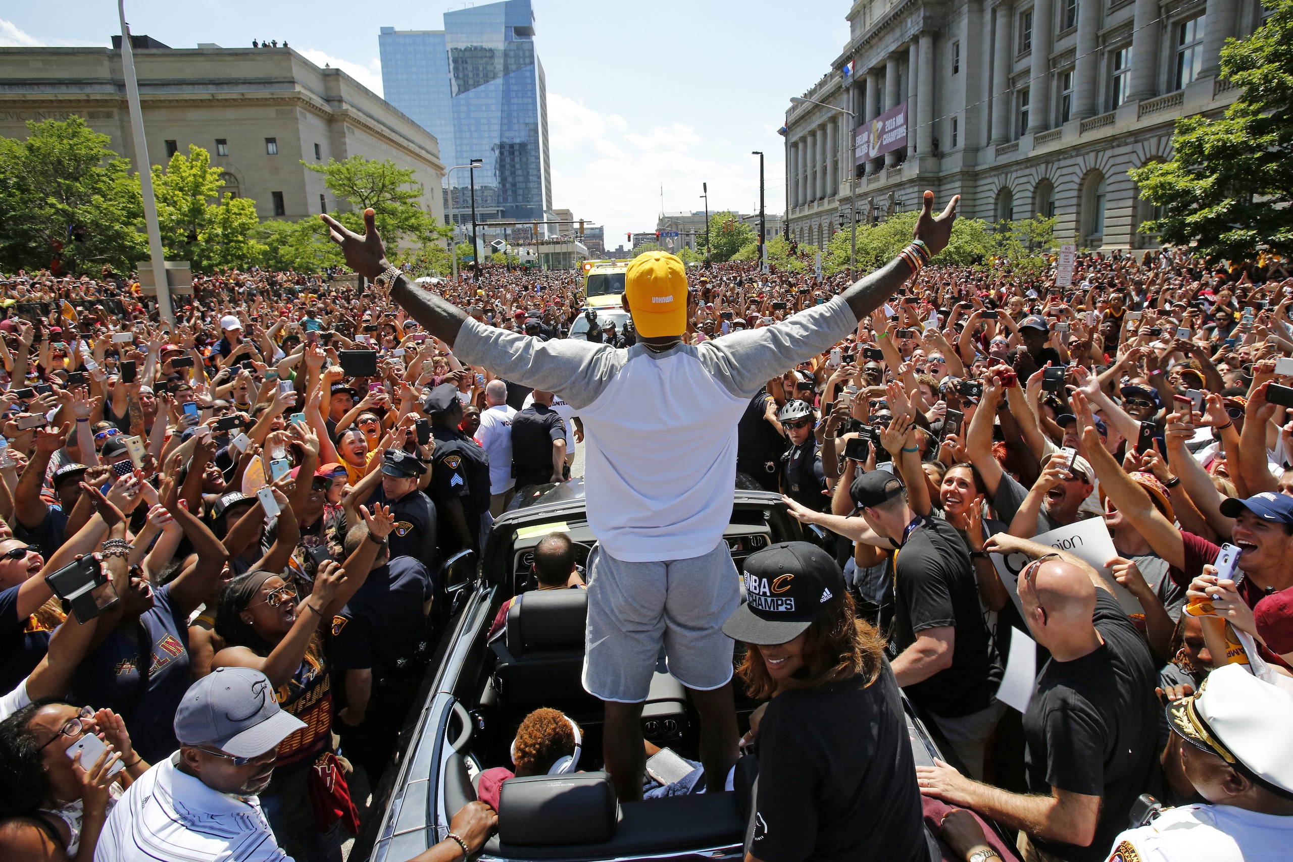 FILE - In this June 22, 2016, file photo, Cleveland Cavaliers' LeBron James, center, stands in the back of a Rolls Royce as it makes its way through the crowd lining the parade route in downtown Cleveland, celebrating the basketball team's NBA championship. When LeBron James and the Cavaliers, whose historic comeback in June against Golden State in the NBA Finals ended Cleveland’s title drought dating to 1964, receive their championship rings and a banner is raised in Quicken Loans Arena before their season opener, the emotional ceremony will merely be the warm-up act. Next door, at Progressive Field, the Indians will host the Chicago Cubs in Game 1 of the World Series. (AP Photo/Gene J. Puskar, File)