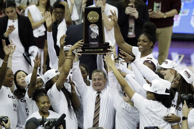 Mississippi State head coach Vic Schaefer holds the regional championship trophy as his team celebrates following a women's NCAA college basketball tournament regional final game against UCLA, Sunday, March 25, 2018, in Kansas City, Mo. Mississippi State defeated UCLA 89-73. (AP Photo/Orlin Wagner)