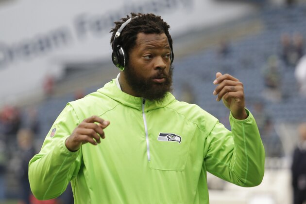 Seattle Seahawks defensive end Michael Bennett wears headphones as he stands on the field during warmups before an NFL football game against the Houston Texans, Sunday, Oct. 29, 2017, in Seattle. (AP Photo/Elaine Thompson)
