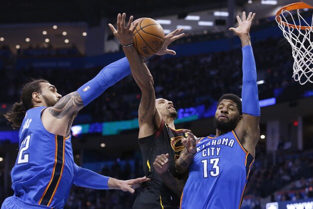 Oklahoma City Thunder center Steven Adams, left, knocks the ball away from Cleveland Cavaliers guard George Hill, center, as Hill shoots in front of forward Paul George (13) during the first half of an NBA basketball game in Oklahoma City, Tuesday, Feb. 13, 2018. (AP Photo/Sue Ogrocki)
