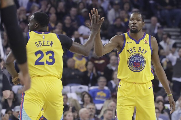 Golden State Warriors forward Draymond Green (23) and forward Kevin Durant (35) celebrate during the first half of an NBA basketball game against the San Antonio Spurs in Oakland, Calif., Thursday, March 8, 2018. (AP Photo/Jeff Chiu)
