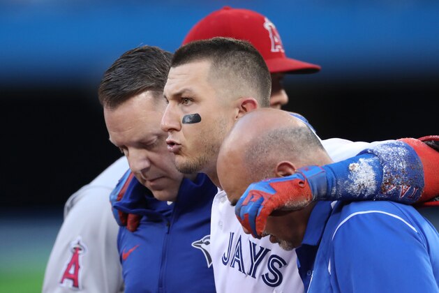 TORONTO, ON - JULY 28: Troy Tulowitzki #2 of the Toronto Blue Jays is helped off the field by trainers George Poulis and Mike Frostad after injuring his ankle in the third inning during MLB game action against the Los Angeles Angels of Anaheim at Rogers Centre on July 28, 2017 in Toronto, Canada. (Photo by Tom Szczerbowski/Getty Images)