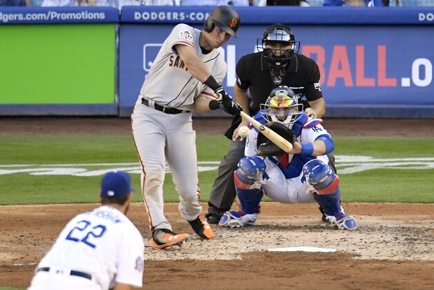 San Francisco Giants' Joe Panik, second from left, hits a solo home run as Los Angeles Dodgers starting pitcher Clayton Kershaw, left, watches along with catcher Yasmani Grandal, right, and home plate umpire Mark Wegner, top right, during the fifth inning of an opening day baseball game Thursday, March 29, 2018, in Los Angeles. (AP Photo/Mark J. Terrill)