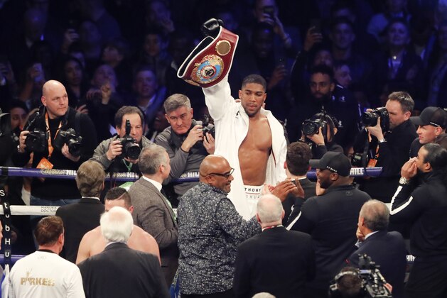 Britain's Anthony Joshua celebrates victory over New Zealand's Joseph Parker, left, after their WBA, IBF, WBO and IBO Heavyweight Championship title bout in Cardiff, Wales, late Saturday, March 31, 2018. (AP Photo/Frank Augstein)