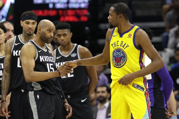 Golden State Warriors forward Kevin Durant, right, shakes hands with Sacramento Kings guard Vince Carter after Warriors guard Patrick McCaw was taken off the court on a stretcher following Carter's Flagrant-1 foul during the third quarter of an NBA basketball game, Saturday, March 31, 2018, in Sacramento, Calif. The Warriors won 112-96. (AP Photo/Rich Pedroncelli)