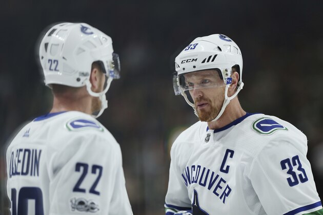 Vancouver Canucks' Daniel Sedin (22) talks with teammate and twin brother Henrik Sedin (33) in the third period of an NHL hockey game against the Minnesota Wild, Tuesday, Oct. 24, 2017, in St. Paul, Minn. Vancouver won 1-0. (AP Photo/Stacy Bengs)
