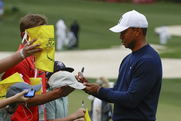 Tiger Woods signs some autographs on the range before a practice round for the Masters golf tournament Wednesday, April 4, 2018, in Augusta, Ga. (AP Photo/Chris Carlson)