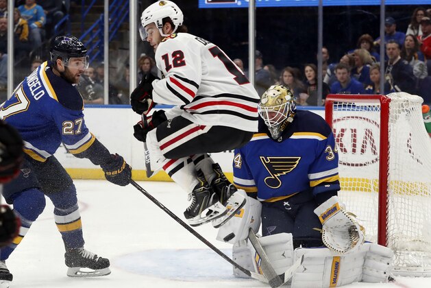 Chicago Blackhawks' Alex DeBrincat (12) leaps out of the way as St. Louis Blues goaltender Jake Allen, right, blocks a shot and Blues' Alex Pietrangelo watches during the third period of an NHL hockey game Wednesday, April 4, 2018, in St. Louis. The Blackhawks won 4-3. (AP Photo/Jeff Roberson)