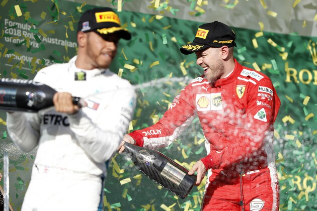 Ferrari driver Sebastian Vettel, right, of Germany and Mercedes driver Lewis Hamilton of Britain spray champagne after the first race of the season at the Australian Formula One Grand Prix in Melbourne, Sunday, March 25, 2018. Vettel won ahead of Hamilton while Ferrari driver Kimi Raikkonen of Finland finished 3rd. (AP Photo/Asanka Brendon Ratnayake)