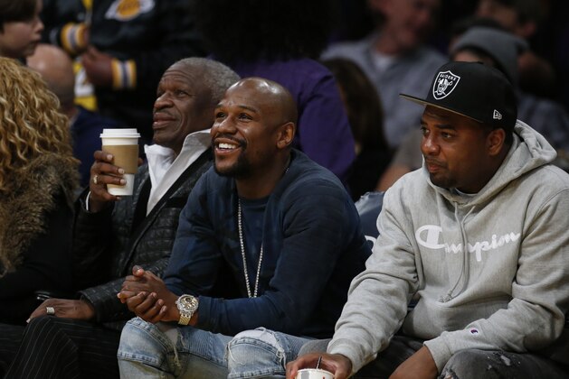 Boxer Floyd Mayweather, center, attends in an NBA basketball game between Los Angeles Lakers and Miami Heat Friday, March 16, 2018, in Los Angeles. (AP Photo/Ringo H.W. Chiu)