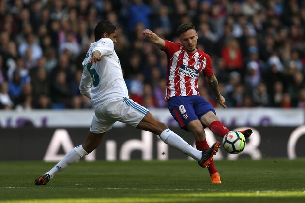 Atletico Madrid's Saul Niguez, right, vies with Real Madrid's Varane during the Spanish La Liga soccer match between Real Madrid and Atletico Madrid at the Santiago Bernabeu stadium in Madrid, Sunday, April 8, 2018. The match ended in a 1-1 draw. (AP Photo/Francisco Seco)
