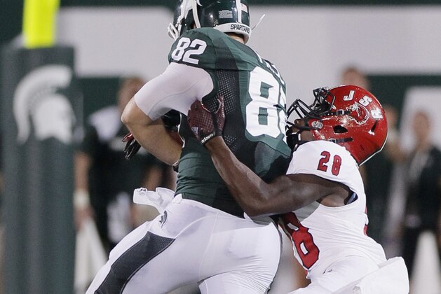 EAST LANSING, MI - AUGUST 29:  Tight end Josiah Price #82 of the Michigan State Spartans is tackled by safety Siran Neal #28 of the Jacksonville State Gamecocks on a 32-yard reception during the second half at Spartan Stadium on August 29, 2014 in East Lansing, Michigan. Michigan State defeated Jacksonville State 45-7. (Photo by Duane Burleson/Getty Images)