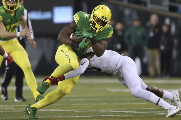 Oregon running back Royce Freeman, center left, is tackled by Arizona's Gavin Robertson Jr. during the first quarter of an NCAA college football game, Saturday, Nov. 18, 2017, in Eugene, Ore. (AP Photo/Chris Pietsch)