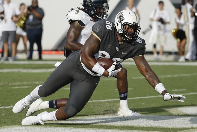 Central Florida's Jordan Akins (88) falls over the goal line after catching a pass in front of Florida International cornerback Andrew Brown (3) for a 22-yard touchdown during the first half of an NCAA college football game, Thursday, Aug. 31, 2017, in Orlando, Fla. (AP Photo/John Raoux)