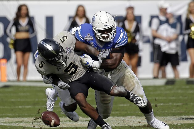 Central Florida wide receiver Dredrick Snelson (5) fumbles the ball as he is hit by Memphis defensive back Jonathan Cook, left, and linebacker Genard Avery, right, during the first half of the American Athletic Conference championship NCAA college football game, Saturday, Dec. 2, 2017, in Orlando, Fla. (AP Photo/John Raoux)
