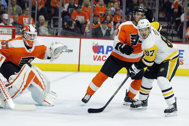 Pittsburgh Penguins' Sidney Crosby, right, positions himself in front of the net and Philadelphia Flyers goalie Brian Elliott, left, and Ivan Provorov during the second period in Game 3 of an NHL first-round hockey playoff series Sunday, April 15, 2018, in Philadelphia, Pa. (AP Photo/Tom Mihalek)