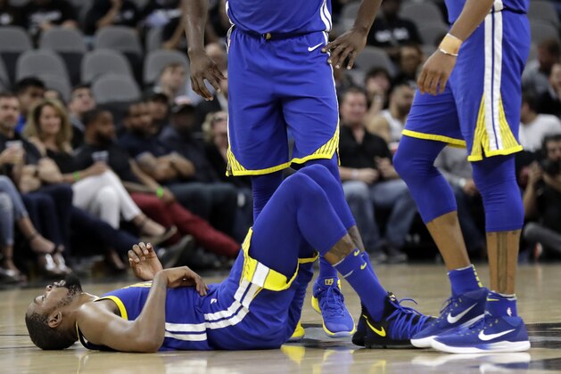 Golden State Warriors' Kevin Durant (35) lies on the court as teammates wait to help him up late in the second half of Game 3 of a first-round NBA basketball playoff series against the San Antonio Spurs in San Antonio, Thursday, April 19, 2018. Golden State won 110-97. (AP Photo/Eric Gay)