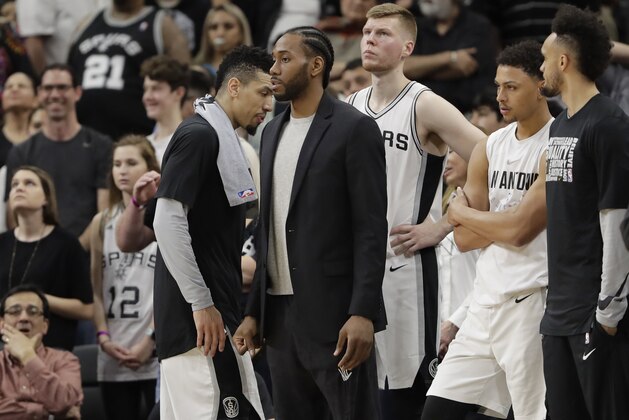 San Antonio Spurs forward Kawhi Leonard, center, waiting to return from injury, wears street cloths as he watches from the bench during the second half of an NBA basketball game against the New Orleans Pelicans, Wednesday, Feb. 28, 2018, in San Antonio. New Orleans won 121-116. (AP Photo/Eric Gay)