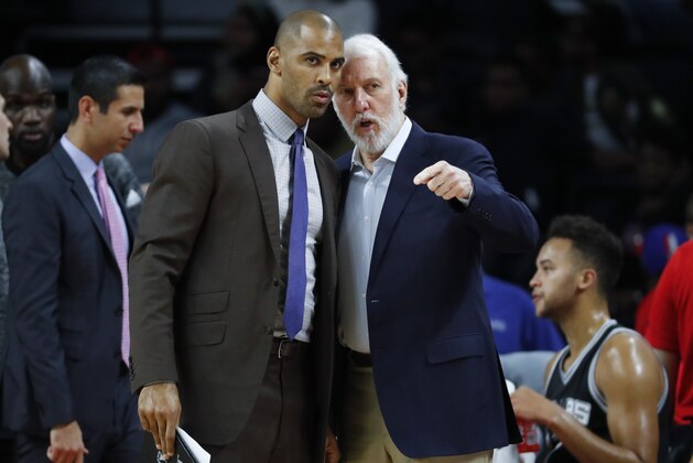 San Antonio Spurs head coach Gregg Popovich, right, talks with assistant Ime Udoka against the Detroit Pistons in the first half of a preseason NBA basketball game in Auburn Hills, Mich., Monday, Oct. 10, 2016. (AP Photo/Paul Sancya)