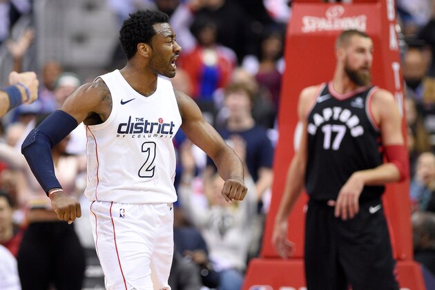 Washington Wizards guard John Wall (2) reacts after his dunk in front of Toronto Raptors center Jonas Valanciunas (17) during the first half of Game 4 of an NBA basketball first-round playoff series, Sunday, April 22, 2018, in Washington. (AP Photo/Nick Wass)