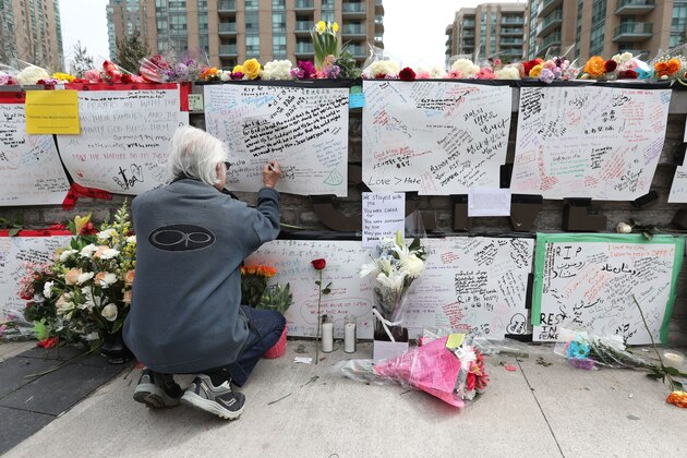 TOPSHOT - Jack Young leaves a notes on April 24, 2018, at a makeshift memorial for victims in the van attack in Toronto, Ontario. - A van driver who ran over 10 people when he plowed onto a busy Toronto sidewalk was charged with murder Tuesday, as Canadian Prime Minister Justin Trudeau urged a rattled nation not to live in fear after the 'senseless attack.' Police said the suspect, 25-year-old Alek Minassian, was not known to them before Monday's carnage in Canada's most populous city, which also left 15 people injured. (Photo by Lars Hagberg / AFP)        (Photo credit should read LARS HAGBERG/AFP/Getty Images)
