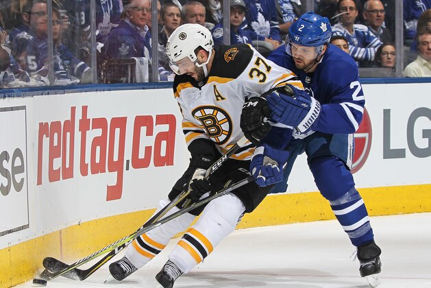 TORONTO, ON - APRIL 23:  Patrice Bergeron #37 of the Boston Bruins controls the puck against Ron Hainsey #2 of the Toronto Maple Leafs in Game Six of the Eastern Conference First Round in the 2018 Stanley Cup Play-offs at the Air Canada Centre on April 23, 2018 in Toronto, Ontario, Canada. The Maple Leafs defeated the Bruins 3-1.(Photo by Claus Andersen/Getty Images) *** Local Caption *** Patrice Bergeron; Ron Hainsey
