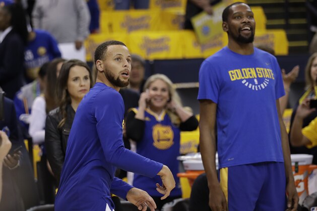 Golden State Warriors' Stephen Curry, left, watches his shot next to teammate Kevin Durant as players warm up for Game 1 of an NBA basketball second-round playoff series against the New Orleans Pelicans,Saturday, April 28, 2018, in Oakland, Calif. (AP Photo/Marcio Jose Sanchez)