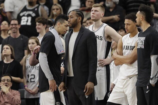 San Antonio Spurs forward Kawhi Leonard, center, waiting to return from injury, wears street cloths as he watches from the bench during the second half of an NBA basketball game against the New Orleans Pelicans, Wednesday, Feb. 28, 2018, in San Antonio. New Orleans won 121-116. (AP Photo/Eric Gay)