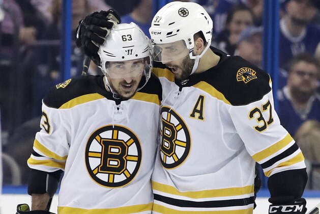 Boston Bruins center Patrice Bergeron (37) hugs left wing Brad Marchand (63) after Bergeron scored against the Tampa Bay Lightning during the third period of Game 1 of an NHL second-round hockey playoff series Saturday, April 28, 2018, in Tampa, Fla. The Bruins won 6-2. (AP Photo/Chris O'Meara)