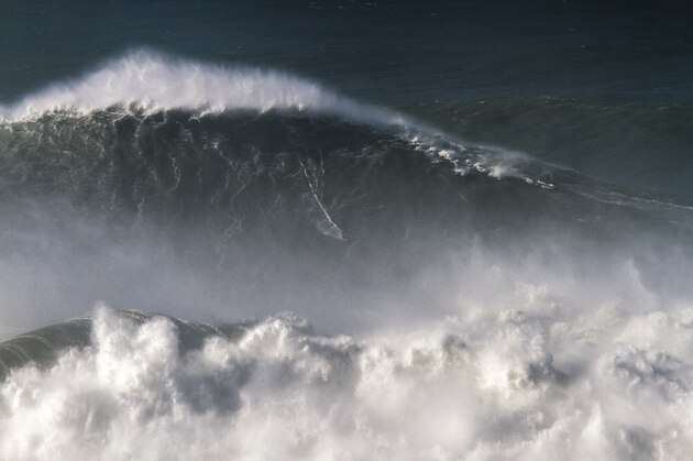 In this photo taken Nov. 8 2017, Brazilian surfer Rodrigo Koxa rides what has been judged the biggest wave ever surfed, at the Praia do Norte, or North beach, in Nazare, Portugal. On Saturday, April 28 2018, the World Surf League credited Koxa with a world record for riding the biggest wave ever surfed and said that its judging panel determined the wave was 80 feet (24.38 meters). (AP Photo/Pedro Cruz)