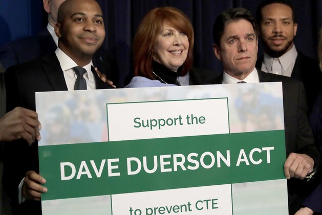 From left, Tregg Duerson, Illinois state Rep. Carol Sente, D-Vernon Hills, and former Chicago Bears' Mike Adamle pose for a photo after a news conference in support of the Dave Duerson Act to Prevent CTE Thursday, Jan. 25, 2018, in Chicago. The Dave Duerson Act is named for the Chicago Bears defensive back who was diagnosed with chronic traumatic encephalopathy after he killed himself at the age of 50, would ban organized tackle football for Illinois children younger than 12 years old. (AP Photo/Charles Rex Arbogast)