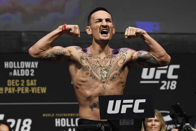 UFC featherweight champion Max Holloway reacts for the crowd during a weigh-in for a mixed martial arts match against Jose Aldo, Friday, Dec. 1, 2017, in Detroit. (AP Photo/Jose Juarez)