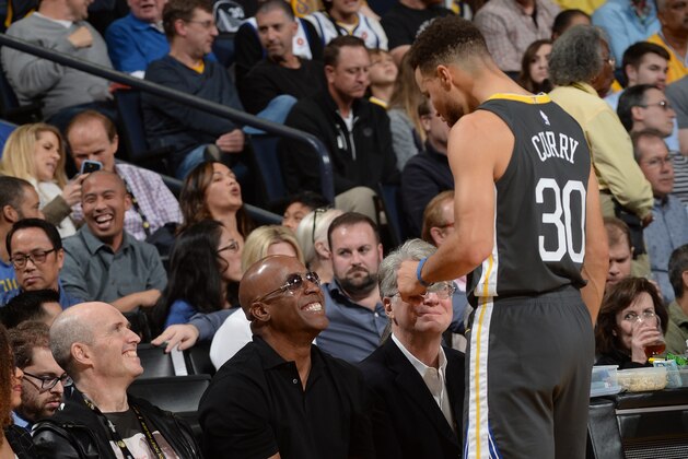 OAKLAND, CA - FEBRUARY 10:  Stephen Curry #30 of the Golden State Warriors and Barry Bonds talk during the game against the San Antonio Spurs on February 10, 2018 at ORACLE Arena in Oakland, California. NOTE TO USER: User expressly acknowledges and agrees that, by downloading and or using this photograph, user is consenting to the terms and conditions of Getty Images License Agreement. Mandatory Copyright Notice: Copyright 2018 NBAE (Photo by Noah Graham/NBAE via Getty Images)