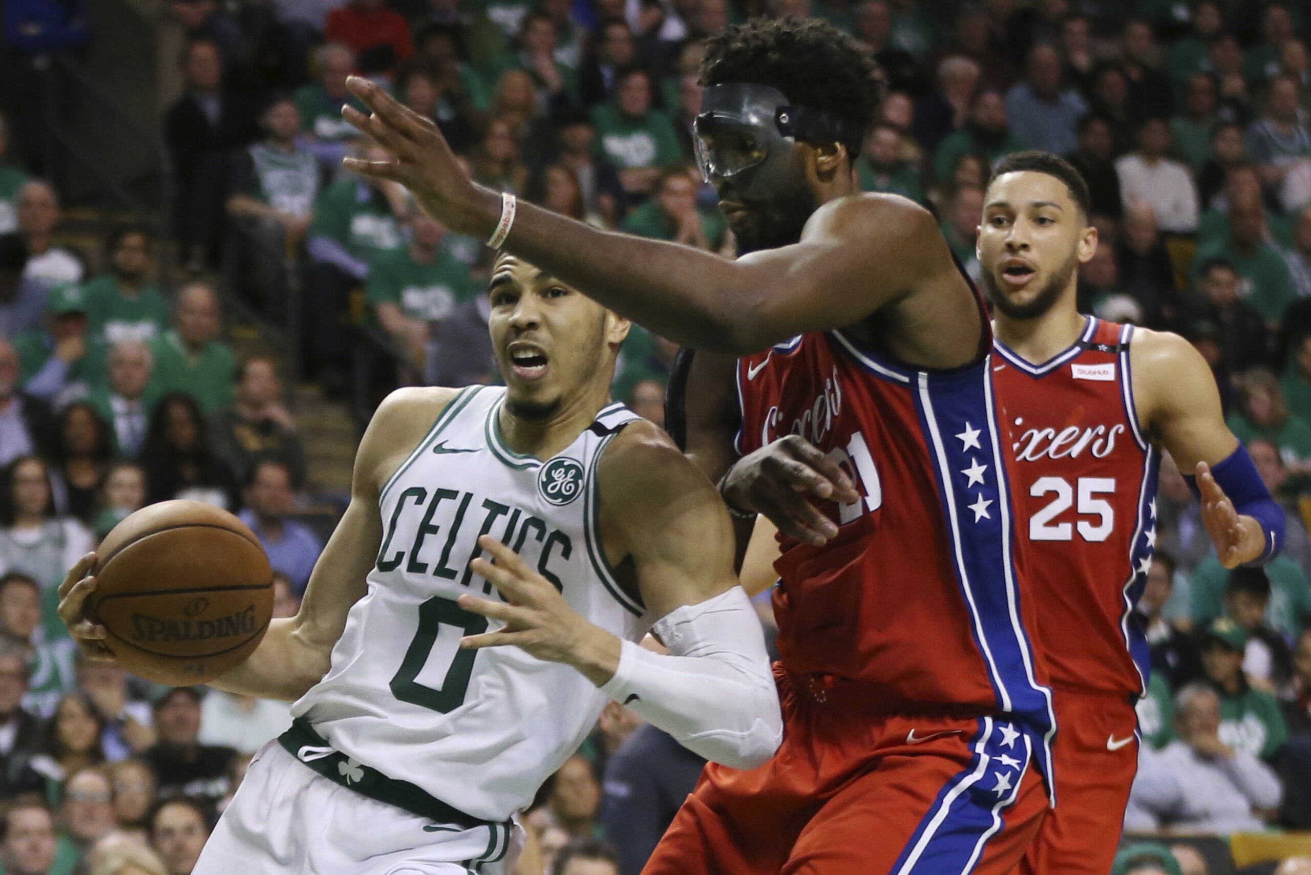 Boston Celtics forward Jayson Tatum (0) drives against Philadelphia 76ers center Joel Embiid (21) as 76ers guard Ben Simmons (25) looks on in the second half of Game 1 of an NBA basketball second-round playoff series, Monday, April 30, 2018, in Boston. The Celtics won 117-101. (AP Photo/Elise Amendola)