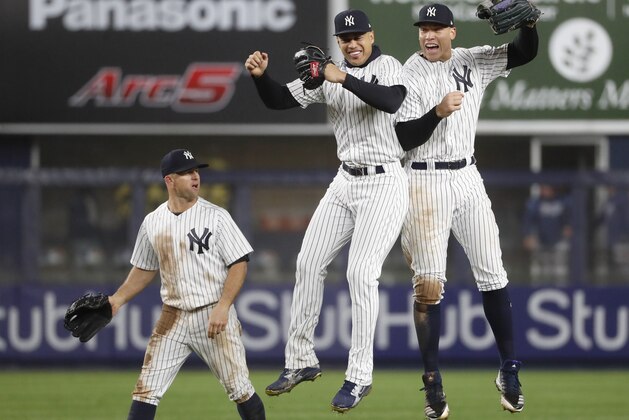 New York Yankees center fielder Brett Gardner, left, watches as Yankees left fielder Giancarlo Stanton, center, and Yankees right fielder Aaron Judge leap in the air after the Yankees 11-4 victory over the Tampa Bay Rays in a baseball game in New York, Tuesday, April 3, 2018. (AP Photo/Kathy Willens)