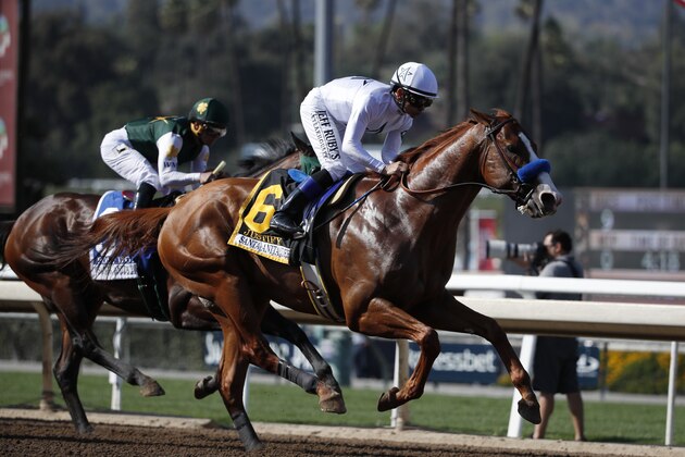 Justify, ridden by Mike Smith, gallops past Bolt d'Oro, background left, with jockey Javier Castellano aboard, during the Santa Anita Derby horse race at Santa Anita on Saturday, April 7, 2018, in Arcadia, Calif. Justify won the race, and Bolt d'Oro came in second. (AP Photo/Jae C. Hong)