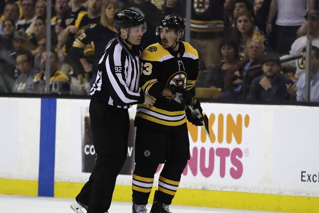 In this May 2, 2018 photo, Boston Bruins left wing Brad Marchand (63) is escorted to the penalty box during the second period of Game 3 of an NHL second-round hockey playoff series against the Tampa Bay Lightning in Boston. The NHL has told  Marchand to stop licking opponents or the Boston Bruins forward will face punishment. Senior vice president of hockey operations Colin Campbell spoke to Marchand and Bruins general manager Don Sweeney on Saturday, May 5 about his actions Friday night against Tampa Bay. Marchand licked Lightning forward Ryan Callahan during Game 4 of their second-round series after appearing to do the same to Toronto’s Leo Komarov earlier in the playoffs. (AP Photo/Charles Krupa)
