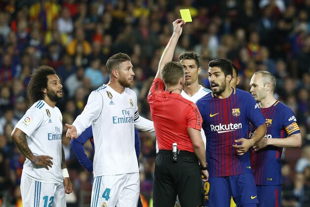 Spanish referee Alejandro Hernandez (C) shows a yellow card to Barcelona's Uruguayan forward Luis Suarez during the Spanish league football match between FC Barcelona and Real Madrid CF at the Camp Nou stadium in Barcelona on May 6, 2018. (Photo by Pau Barrena / AFP)        (Photo credit should read PAU BARRENA/AFP/Getty Images)