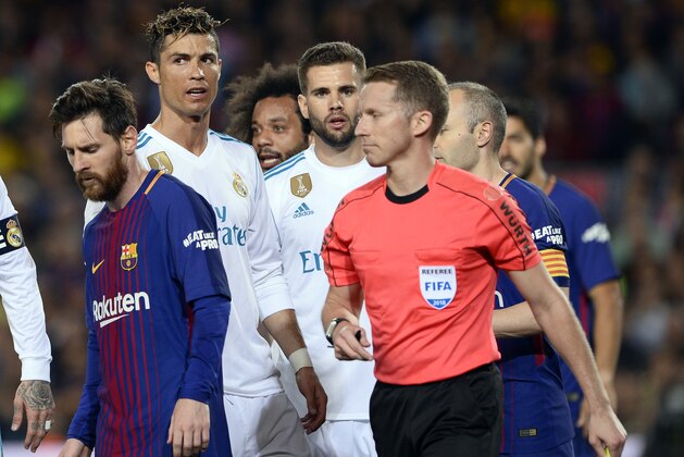 Spanish referee Hernandez Hernandez walks past Barcelona's Argentinian forward Lionel Messi (L) and Real Madrid's Portuguese forward Cristiano Ronaldo (2L) during the Spanish league football match between FC Barcelona and Real Madrid CF at the Camp Nou stadium in Barcelona on May 6, 2018. (Photo by Josep LAGO / AFP)        (Photo credit should read JOSEP LAGO/AFP/Getty Images)