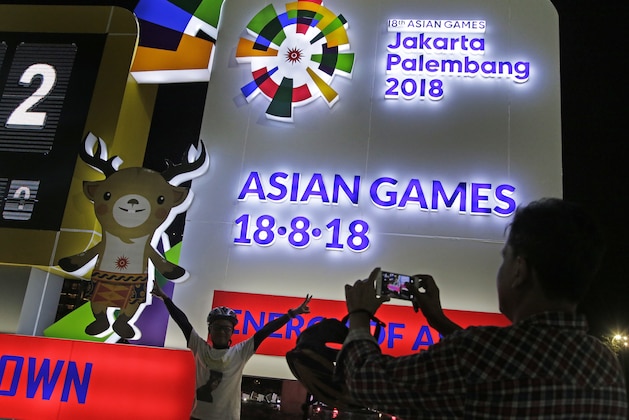 A man has his photo taken at the one-year countdown clock to the 2018 Asian Games in Jakarta, Indonesia, Friday, Aug. 18, 2017. Indonesia started the countdown clock Friday as it races to complete venues to host the games that it hopes will showcase the archipelago as a leading nation in the region and boost its perennially light medal total. (AP Photo/Dita Alangkara)