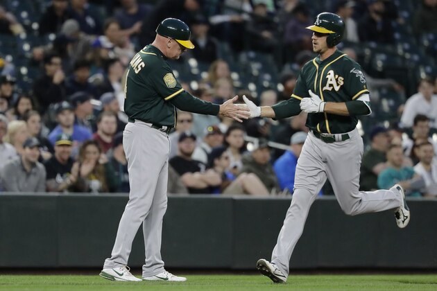 Oakland Athletics' Stephen Piscotty, right, greets third base coach Matt Williams after Piscotty hit a solo home run during the fifth inning of a baseball game against the Seattle Mariners, Thursday, May 3, 2018, in Seattle. (AP Photo/Ted S. Warren)