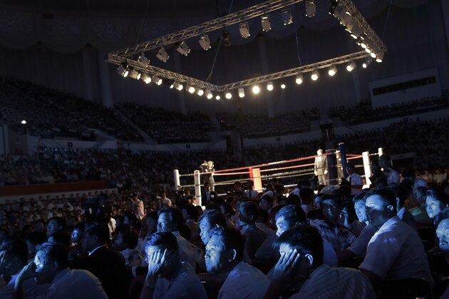 The faces of North Koreans are illuminated by stage lighting as they watch pro wrestlers enter the arena, Saturday, Aug. 30, 2014 in Pyongyang, North Korea. North Koreans got their first look at pro wrestling in about 20-years on Saturday when former NFL lineman Bob