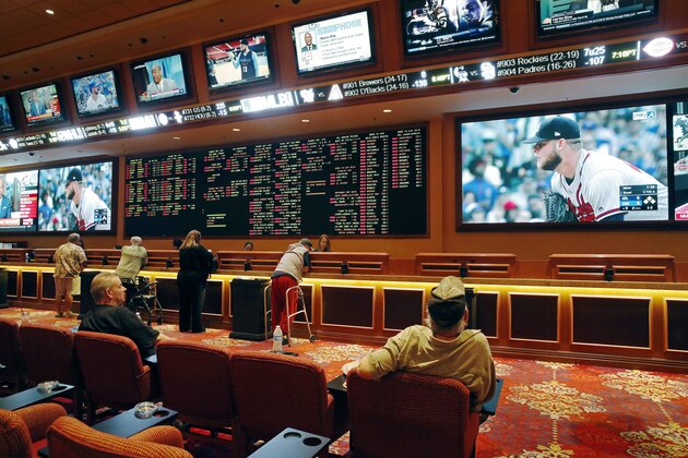 In this Monday, May 14, 2018 photo, people make bets in the sports book at the South Point hotel and casino in Las Vegas. Now that the U.S. Supreme Court has cleared the way for states to legalize sports betting, the race is on to see who will referee the multi-billion-dollar business expected to emerge from the decision.  (AP Photo/John Locher)
